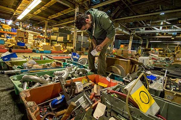 Person standing on top of items sorting through industrial surplus items.