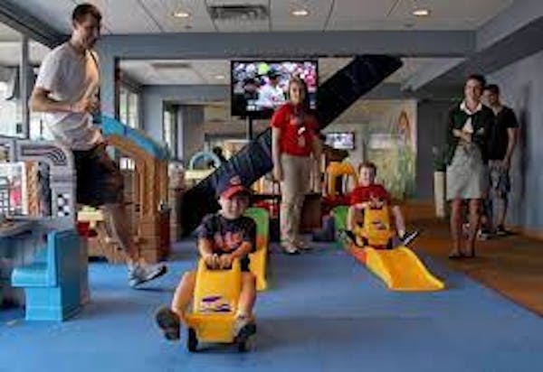 Staff member wearing red shirt observing children playing in Kids Clubhouse at ballpark