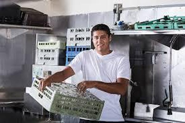 Person smiling and holding a tray for cups out of a dishwasher machine 