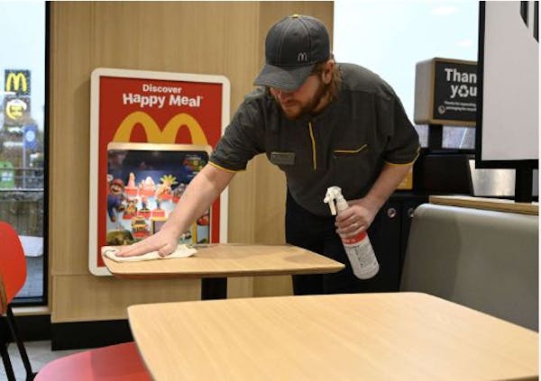 Person with spray bottle wiping table at a McDonald's