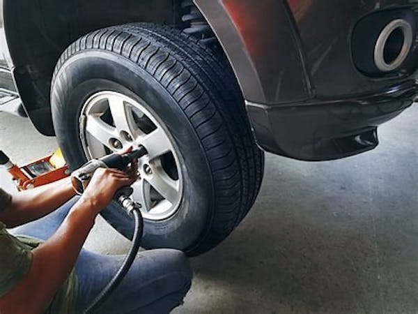 Person installing new tires onto vehicle.