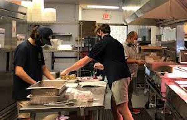 3 line cooks working in a small concession stand kitchen 