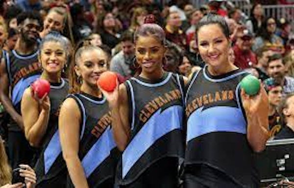 Group of individuals wearing Cavaliers jerseys holding balls to throw into crowd