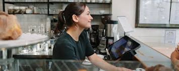 Person using a Point of Sales register smiling at customers