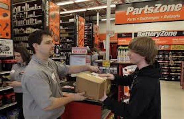 Worker in gray shirt handing box to customer at Autozone