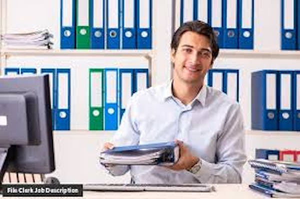 Person in white button down by computer holding a binder