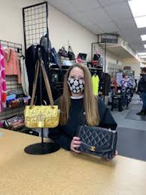 Person holding a handbag at the counter preparing it for resale
