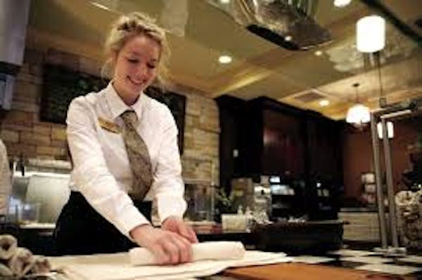 Person smiling while rolling silverware in white napkins 