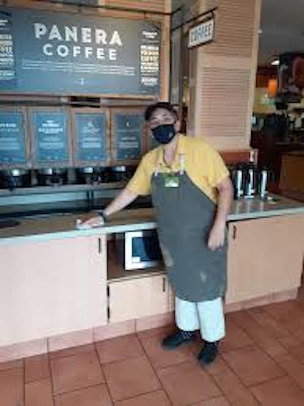 Person wearing wiping down a counter in Panera Bread
