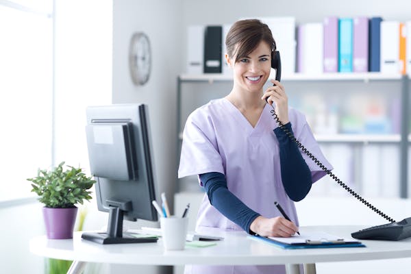 Person wearing scrubs talking on phone in an office setting