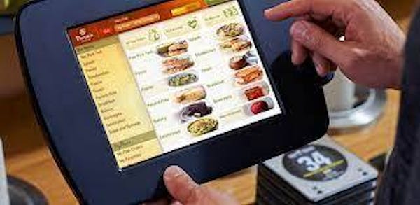 Hand using a touch screen POS system with Panera items