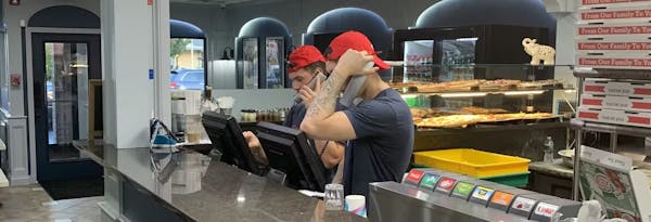 Two people with red hats answering phones behind a counter.