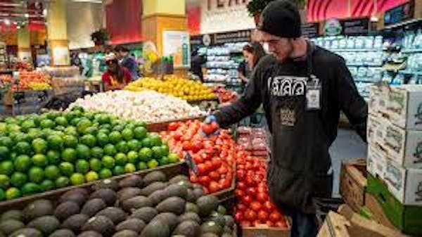 Person working on stocking vegetables in a grocery setting