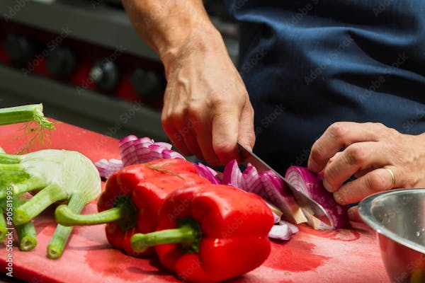 Image of hands using a knife to slice veggies.