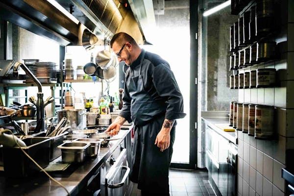 Person wearing a black chef's coat in a large kitchen