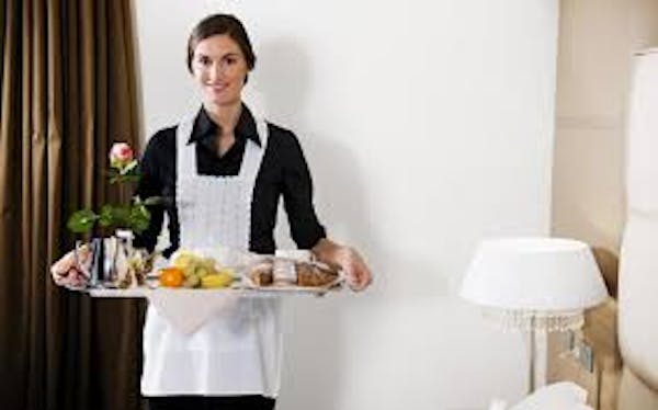 Person in white apron holding tray of food with flowers on them