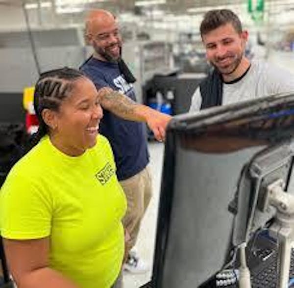 3 people smiling and looking a computer