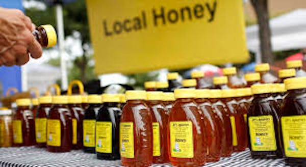 Jars of honey on table with a "Local honey" sign above