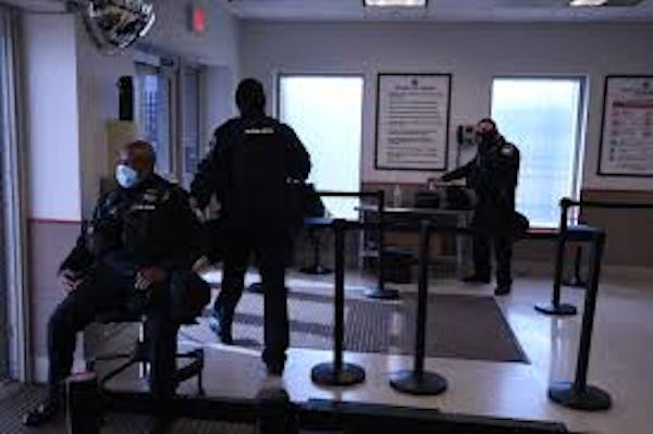 Person in security uniform seated at entrance to area within building