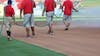 Crew holding a hose spraying field at professional baseball ballpark