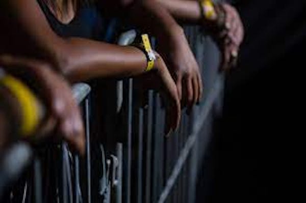 People standing behind fence with wristbands on their arms