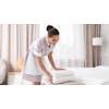 Person in hotel room folding white towels on top of bed