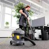 Person vacuuming in an office setting.