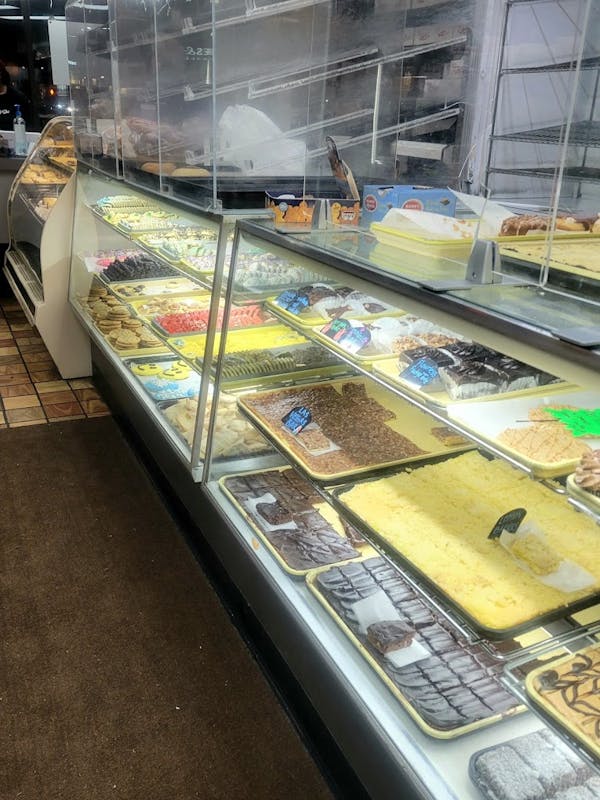 Bakery case with clear glass windows and yellow trays displaying assorted pastry and cookies.