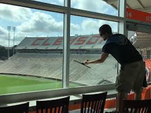 Person cleaning windows inside a suite at football stadium