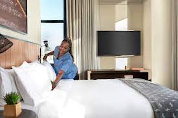 Person adjusting pillow on bed in hotel room