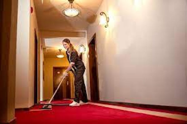 Person sweep floor in long hallway in hotel
