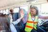 Female bus driver high fiving child