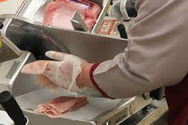 Person slicing deli meats on meat slicer