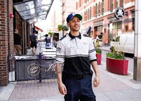 Person in street wearing safety ambassador polo with hat