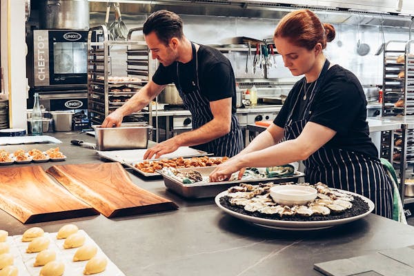 People working in a kitchen environment prepping food on tray