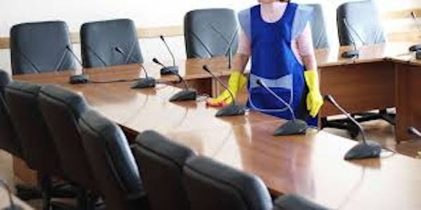 Person wiping down conference room table 