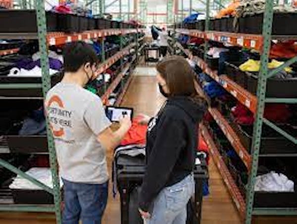 2 people looking at a device to sort items in the warehouse.