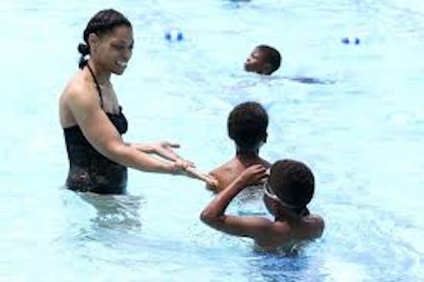 Person who appears as an adult in pool helping children in the water