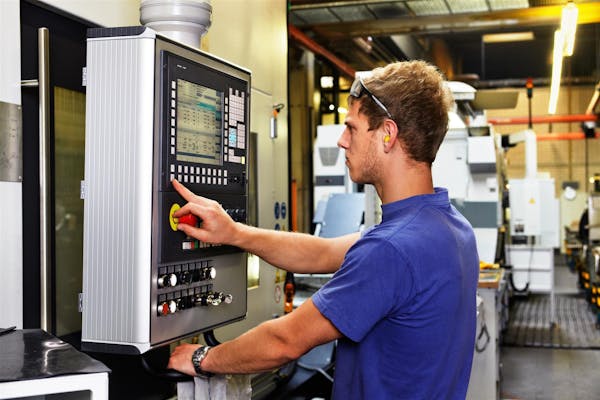 Person looking at a CNC machine and pressing buttons